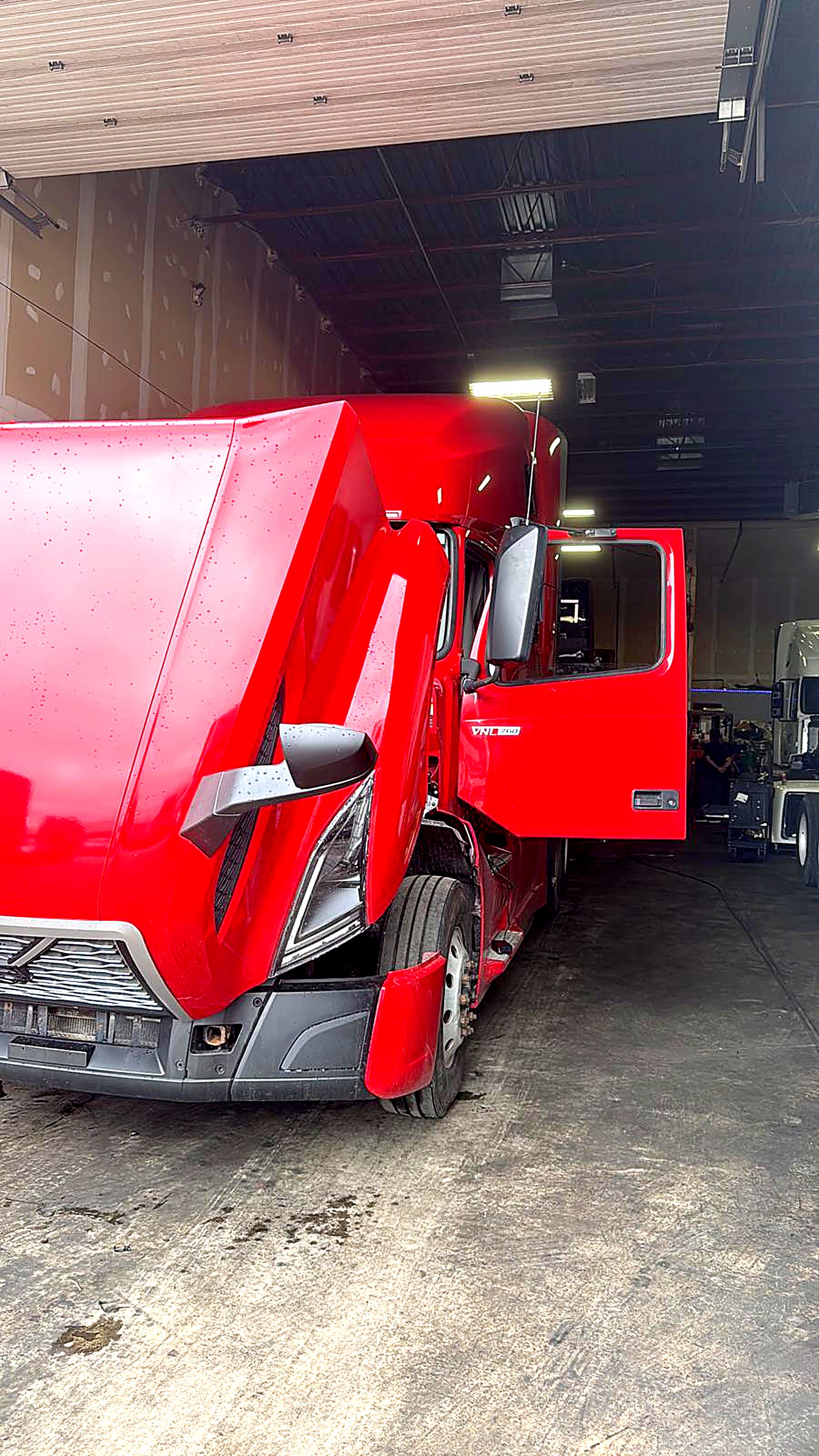 Red semi-truck tractor in the service bay at a heavy-duty repair shop